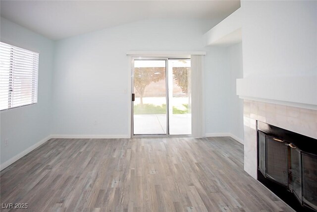 5233 Camino Del Rancho, Las Vegas, NV 89130 - unfurnished living room featuring a tiled fireplace, vaulted ceiling, and wood finished floors