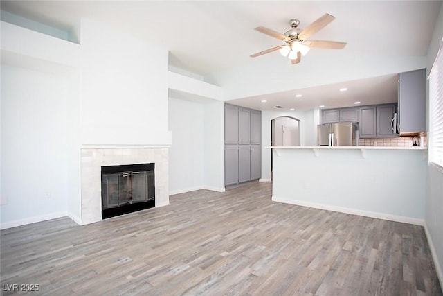 5233 Camino Del Rancho, Las Vegas, NV 89130 - unfurnished living room featuring a ceiling fan, light wood finished floors, high vaulted ceiling, a tile fireplace, and recessed lighting