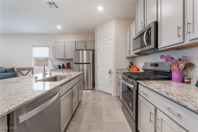 7910 Shimmery St, North Las Vegas, NV 89084 - kitchen with stainless steel appliances, light stone counters, gray cabinets, and recessed lighting