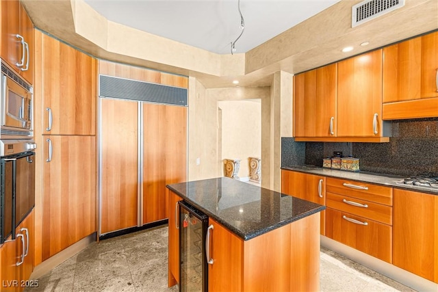 2877 Paradise Rd Unit 702, Las Vegas, NV 89109 - kitchen with built in appliances, beverage cooler, brown cabinetry, dark stone counters, and backsplash