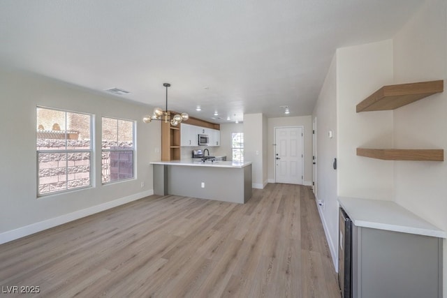 1097 Paradise Resort Dr, Henderson, NV 89002 - unfurnished living room with a chandelier, plenty of natural light, light wood-style flooring, and beverage cooler