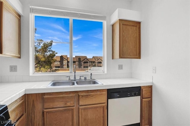 5155 W Tropicana Ave Unit 2017, Las Vegas, NV 89103 - kitchen featuring white dishwasher, brown cabinetry, plenty of natural light, and tile counters