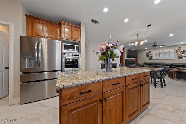 2637 Ohio Ct, Las Vegas, NV 89128 - kitchen featuring appliances with stainless steel finishes, light marble finish flooring, brown cabinetry, light stone counters, and ceiling fan