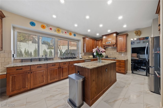 2637 Ohio Ct, Las Vegas, NV 89128 - kitchen with light marble finish floors, brown cabinetry, a kitchen island, backsplash, and light stone counters