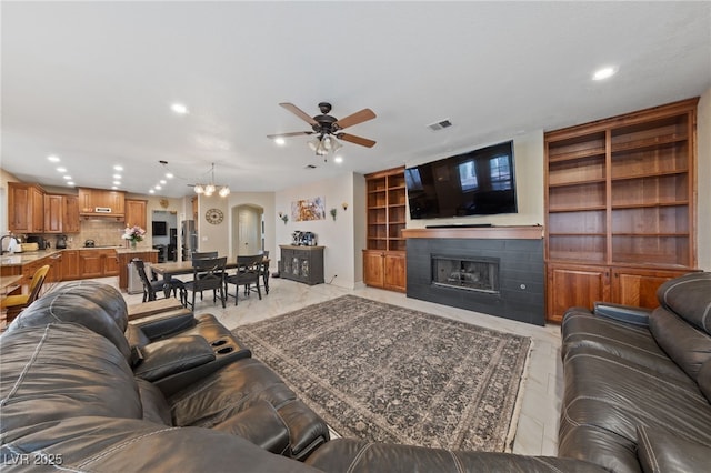 2637 Ohio Ct, Las Vegas, NV 89128 - living room featuring recessed lighting, a ceiling fan, a fireplace, arched walkways, and built in shelves