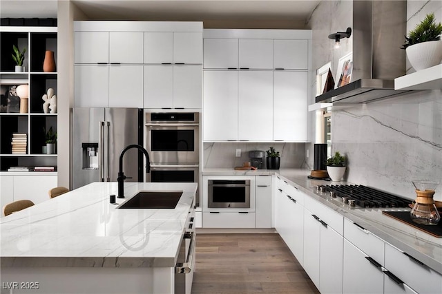 650 Agate Bridge St, Las Vegas, NV 89138 - kitchen with stainless steel appliances, wall chimney range hood, a kitchen island with sink, wood finished floors, and modern cabinets