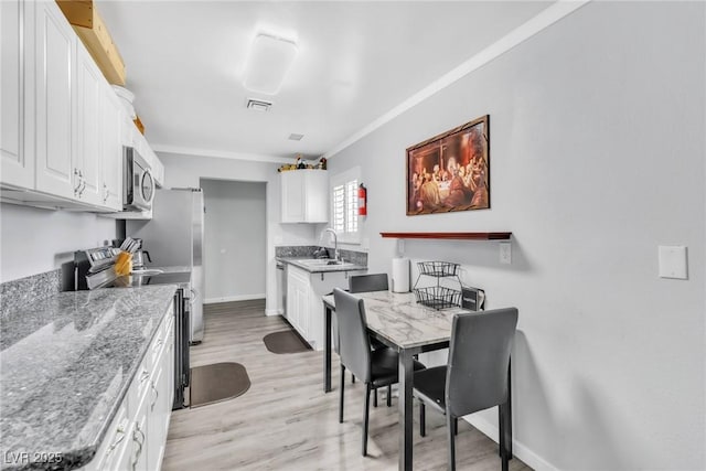 3499 Middlebury Ave, Las Vegas, NV 89121 - kitchen featuring stainless steel appliances, ornamental molding, white cabinets, light wood-type flooring, and light stone counters