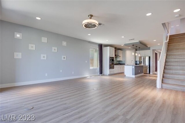 10342 Kesington Dr, Las Vegas, NV 89135 - unfurnished living room featuring stairway, recessed lighting, and light wood finished floors