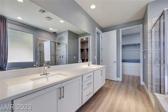 10342 Kesington Dr, Las Vegas, NV 89135 - full bathroom featuring a stall shower, a walk in closet, double vanity, and wood finished floors