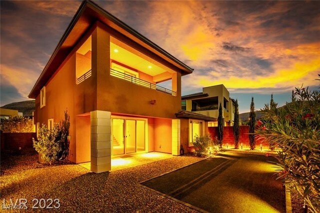 10342 Kesington Dr, Las Vegas, NV 89135 - back of property at dusk with a balcony and stucco siding