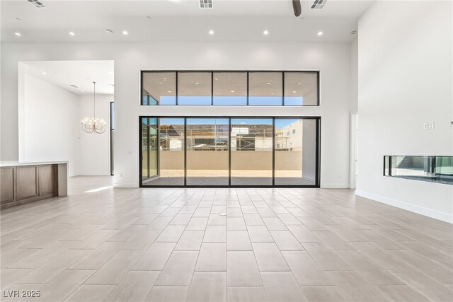 10919 Vista Altura Ave, Las Vegas, NV 89135 - unfurnished living room with a towering ceiling, a chandelier, and recessed lighting