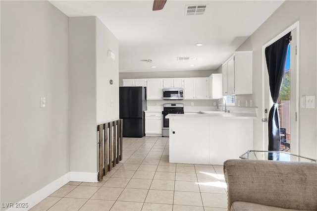 5200 Paradise Skies Ave, Las Vegas, NV 89156 - kitchen featuring appliances with stainless steel finishes, light tile patterned flooring, a peninsula, white cabinets, and recessed lighting