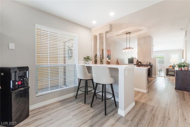 4909 Desert Poppy Dr, Las Vegas, NV 89130 - kitchen featuring a peninsula, light wood finished floors, a breakfast bar area, hanging light fixtures, and light countertops