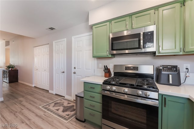 4909 Desert Poppy Dr, Las Vegas, NV 89130 - kitchen featuring stainless steel appliances, green cabinetry, light countertops, and light wood-style flooring