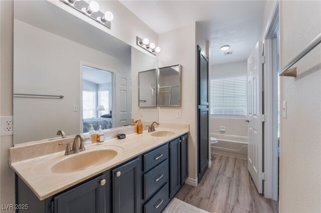 4909 Desert Poppy Dr, Las Vegas, NV 89130 - bathroom with double vanity, a garden tub, wood finished floors, and ensuite bathroom