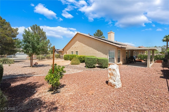 4909 Desert Poppy Dr, Las Vegas, NV 89130 - back of house with a patio area, a chimney, stucco siding, roof mounted solar panels, and a tiled roof