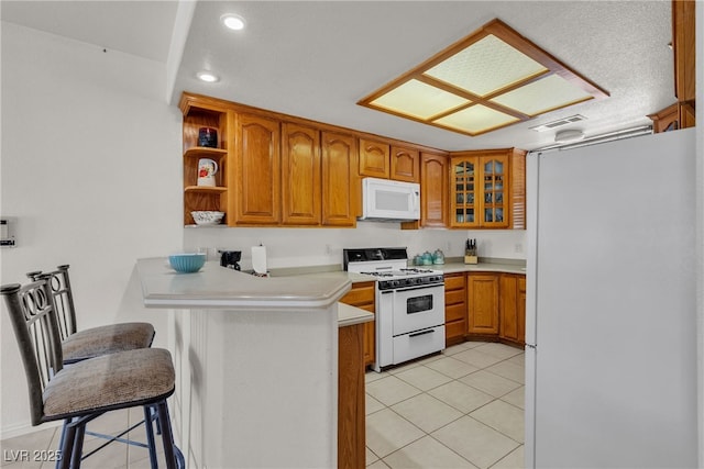 825 W Ryan Ave, Overton, NV 89040 - kitchen featuring white appliances, a peninsula, light tile patterned floors, brown cabinets, and recessed lighting