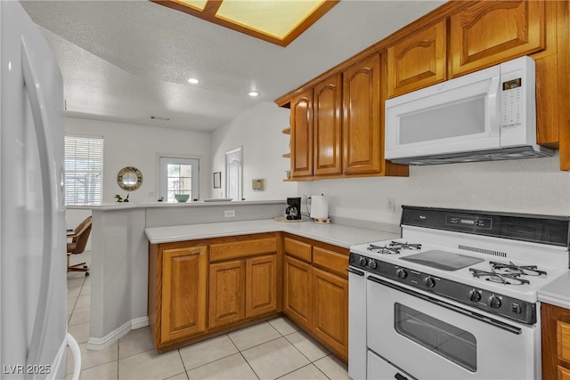 825 W Ryan Ave, Overton, NV 89040 - kitchen with white appliances, a peninsula, brown cabinets, light tile patterned floors, and a textured ceiling