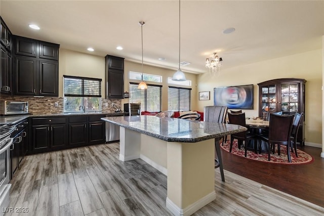 6705 Philharmonic Ave, Las Vegas, NV 89139 - kitchen with a breakfast bar, dishwasher, light wood-type flooring, a center island, and tasteful backsplash