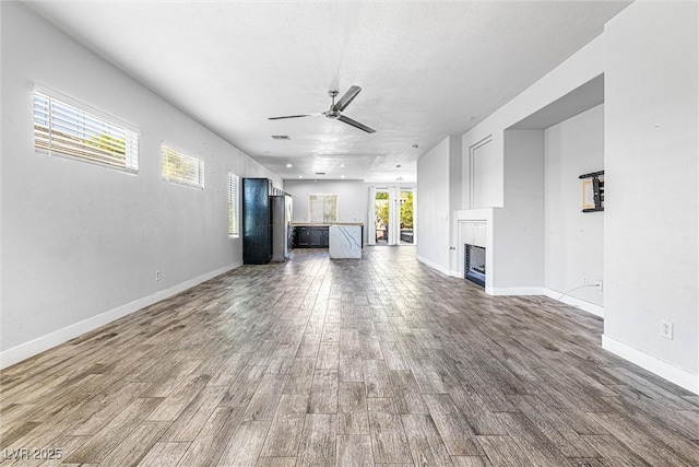 3257 Rushing Waters Pl, Las Vegas, NV 89135 - unfurnished living room featuring a ceiling fan, dark wood finished floors, and a fireplace