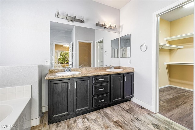 3257 Rushing Waters Pl, Las Vegas, NV 89135 - bathroom featuring wood finished floors, double vanity, a bath, and a spacious closet