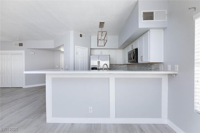 4820 Grey Wolf Ln Unit 101, Las Vegas, NV 89149 - kitchen with stainless steel appliances, white cabinetry, light wood-style flooring, decorative backsplash, and light countertops