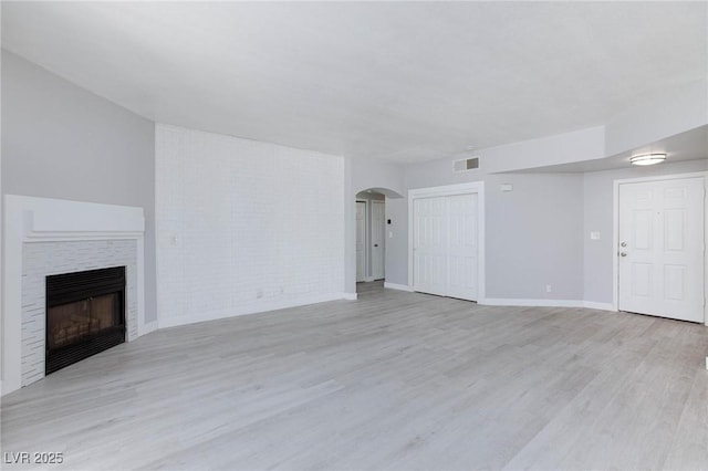 4820 Grey Wolf Ln Unit 101, Las Vegas, NV 89149 - unfurnished living room with arched walkways, a fireplace, and wood finished floors