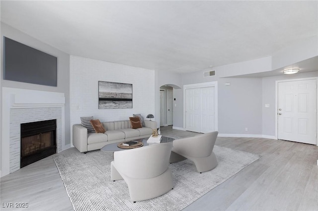 4820 Grey Wolf Ln Unit 101, Las Vegas, NV 89149 - living room featuring arched walkways, light wood finished floors, and a fireplace