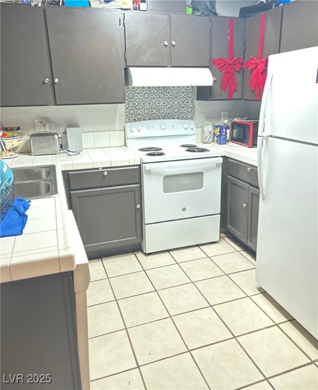 2698 Alicialynn Way, Las Vegas, NV 89121 - kitchen with white appliances, range hood, tile countertops, gray cabinetry, and light tile patterned flooring