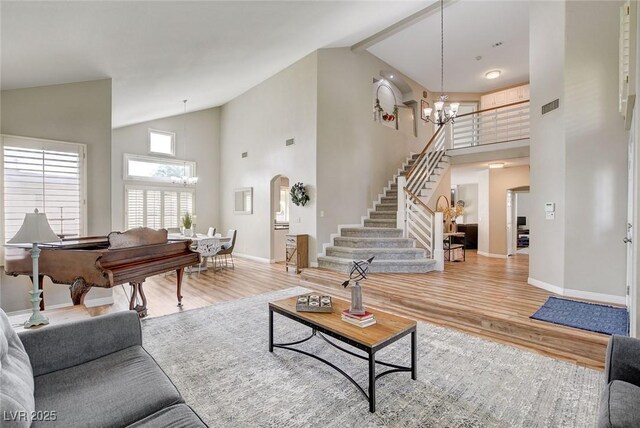 2073 Sapphire Valley Ave, Henderson, NV 89074 - living area featuring a chandelier, stairs, light wood-style flooring, high vaulted ceiling, and arched walkways