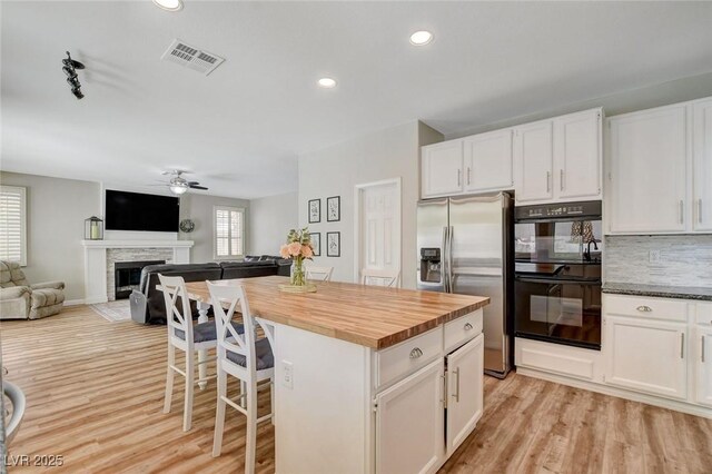 2073 Sapphire Valley Ave, Henderson, NV 89074 - kitchen with stainless steel fridge with ice dispenser, a ceiling fan, white cabinetry, wooden counters, and a fireplace