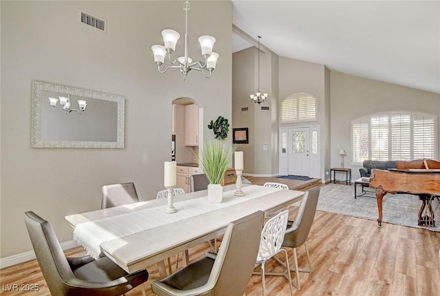 2073 Sapphire Valley Ave, Henderson, NV 89074 - dining room featuring a chandelier, high vaulted ceiling, arched walkways, and light wood-style flooring