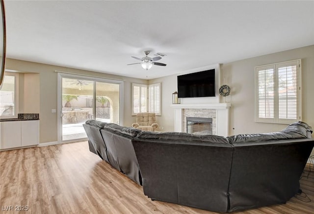2073 Sapphire Valley Ave, Henderson, NV 89074 - living area featuring a stone fireplace, ceiling fan, and light wood finished floors