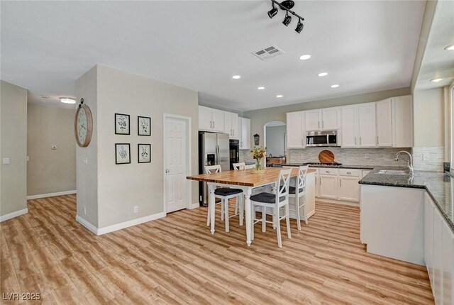 2073 Sapphire Valley Ave, Henderson, NV 89074 - kitchen featuring appliances with stainless steel finishes, arched walkways, light wood-style floors, white cabinetry, and recessed lighting
