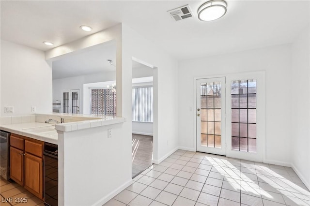 1911 Hobson Dr, Henderson, NV 89074 - kitchen with brown cabinets, tile countertops, light tile patterned floors, recessed lighting, and stainless steel dishwasher