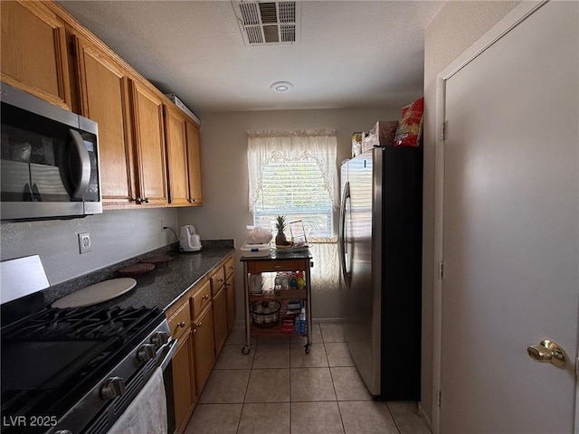 8898 Promised Land Ave, Las Vegas, NV 89148 - kitchen featuring stainless steel appliances, light tile patterned floors, and brown cabinets