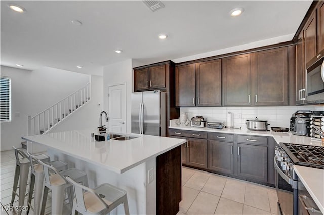 7853 Bethel Heights Ln, Las Vegas, NV 89113 - kitchen with appliances with stainless steel finishes, light tile patterned flooring, light countertops, dark brown cabinets, and a breakfast bar area