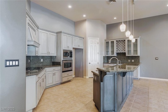 5193 N Miller Ln, Las Vegas, NV 89149 - kitchen with stainless steel appliances, glass insert cabinets, backsplash, dark stone counters, and light tile patterned floors