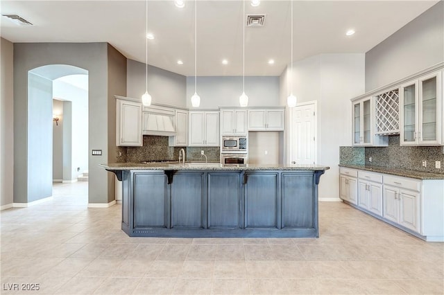 5193 N Miller Ln, Las Vegas, NV 89149 - kitchen with arched walkways, tasteful backsplash, custom range hood, stainless steel appliances, and recessed lighting