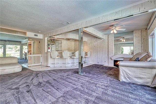 940 Vegas Valley Dr, Las Vegas, NV 89109 - carpeted living area featuring ceiling fan, a textured ceiling, a fireplace, and wood walls