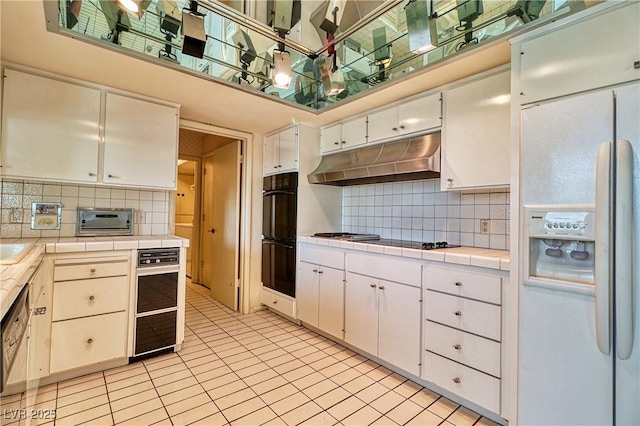 940 Vegas Valley Dr, Las Vegas, NV 89109 - kitchen featuring black appliances, tile counters, under cabinet range hood, decorative backsplash, and a towering ceiling