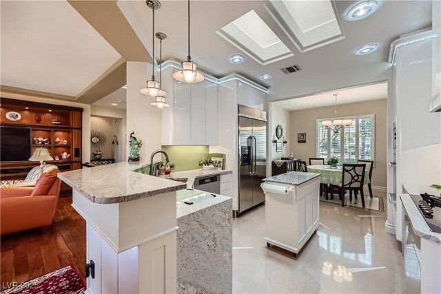 1897 Holdenville St, Henderson, NV 89052 - kitchen featuring stainless steel appliances, a peninsula, white cabinetry, and a kitchen island