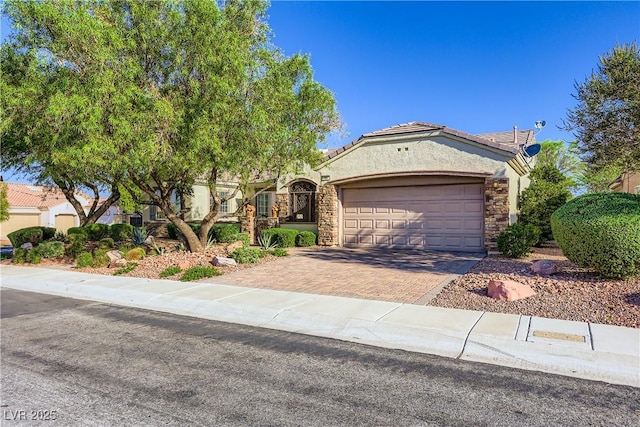 1897 Holdenville St, Henderson, NV 89052 - view of front of property with a garage, decorative driveway, stucco siding, a tile roof, and stone siding