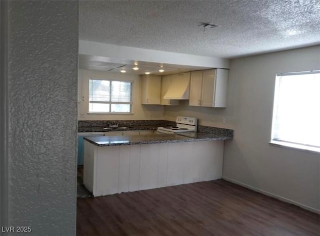 4451 Rich Dr Unit D, Las Vegas, NV 89102 - kitchen featuring white electric range, a peninsula, dark wood-style flooring, a textured ceiling, and ventilation hood