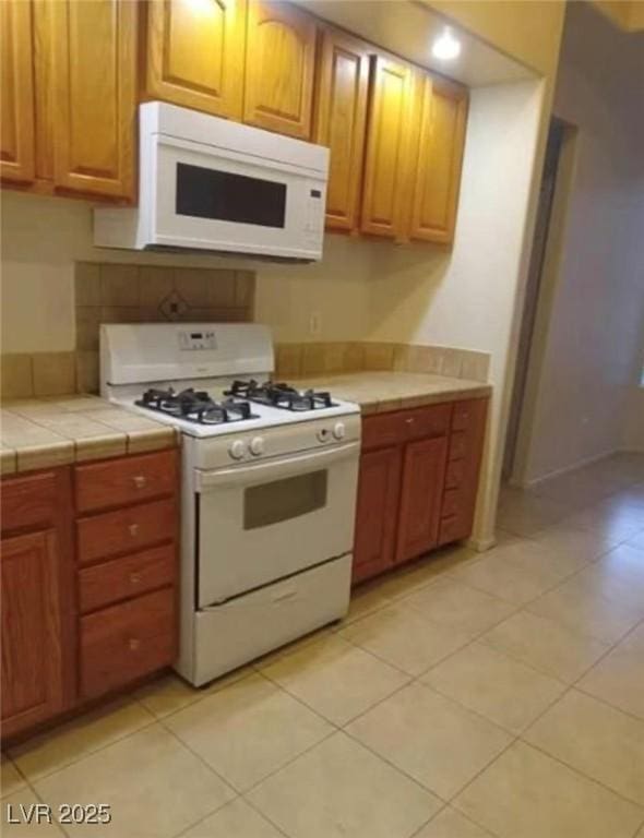 3237 Perching Bird Ln, North Las Vegas, NV 89084 - kitchen featuring white appliances, tile counters, and light tile patterned floors