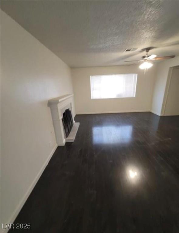 3755 Chutney St, Las Vegas, NV 89121 - unfurnished living room featuring ceiling fan, a fireplace with raised hearth, dark wood-style flooring, and a textured ceiling