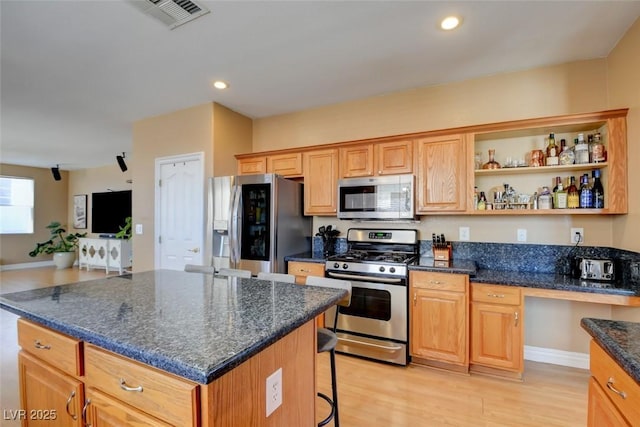 98 Milicity Rd, Henderson, NV 89012 - kitchen featuring stainless steel appliances, a kitchen bar, light wood-style flooring, a kitchen island, and dark stone countertops