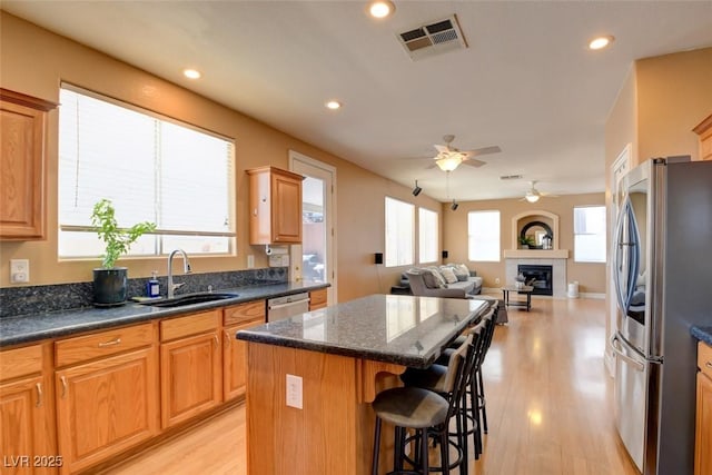 98 Milicity Rd, Henderson, NV 89012 - kitchen with stainless steel appliances, a kitchen island, ceiling fan, a breakfast bar, and a fireplace