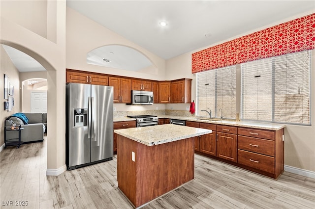 9733 Northern Dancer Dr, Las Vegas, NV 89117 - kitchen featuring stainless steel appliances, high vaulted ceiling, a center island, light wood-type flooring, and arched walkways