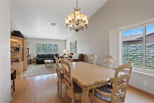 3361 Iberia St, Las Vegas, NV 89146 - dining room featuring vaulted ceiling, a chandelier, light wood-type flooring, and a textured ceiling